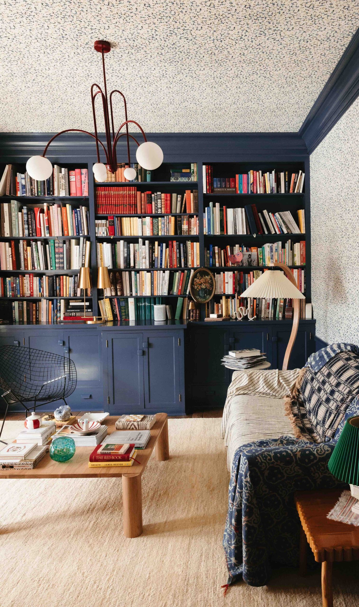 A library and home office features A-Street Prints floral wallpaper and a large built-in blue bookshelf 