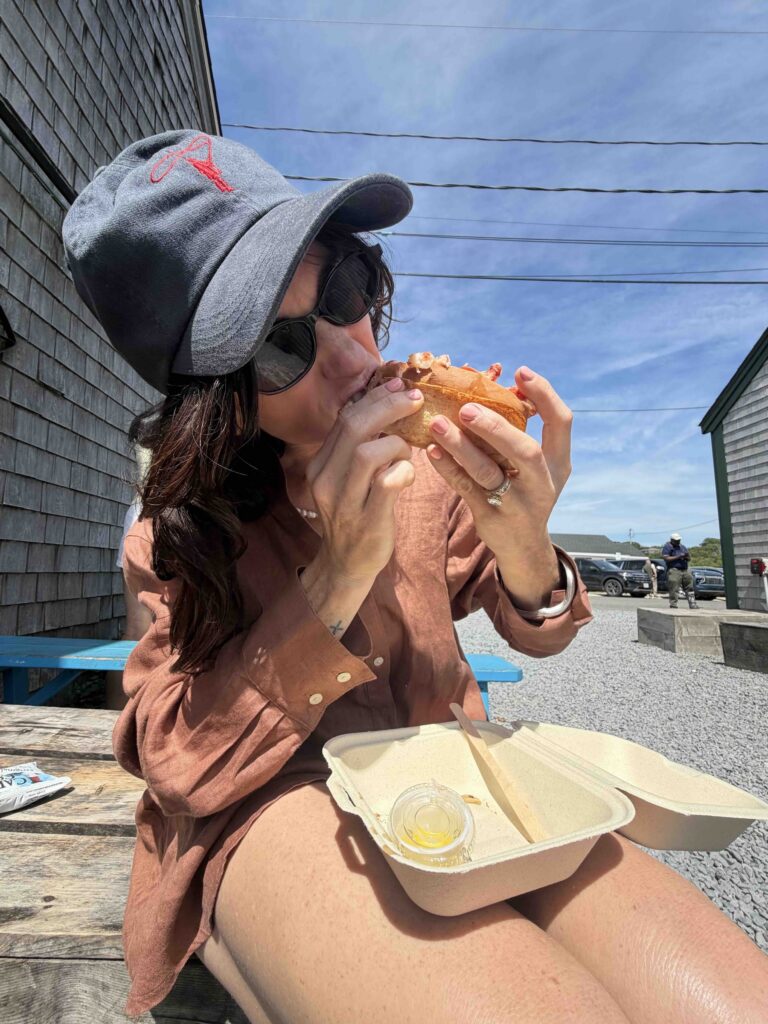 Martha's Vineyard woman eating a Lobster Roll on a bench outside
