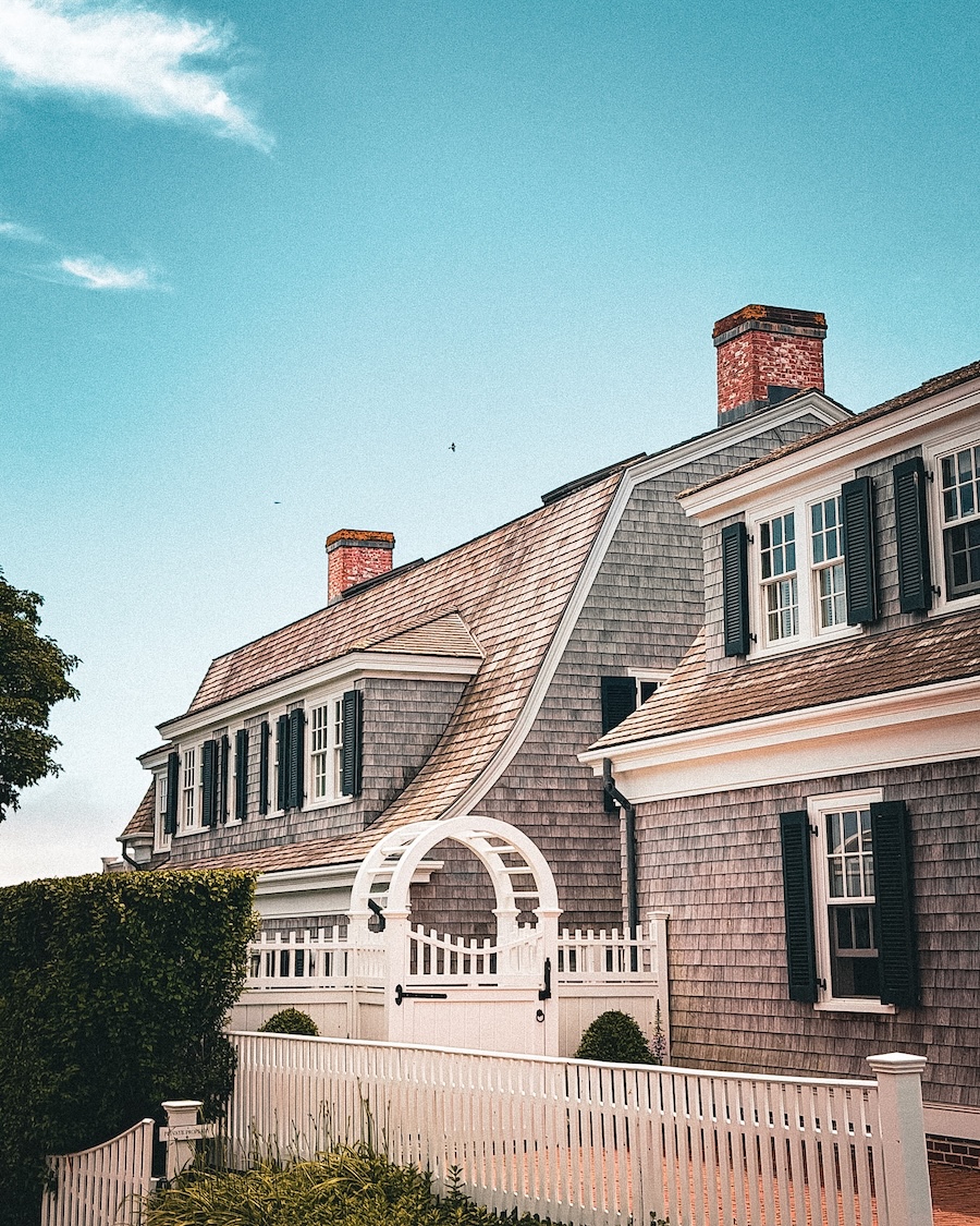 Cedar shingled house with white picket fence and brick chimneys in martha's vineyard